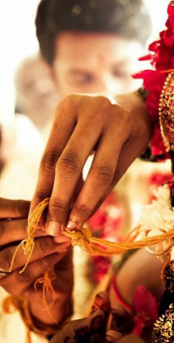 A groom fastening a ceremonial thread