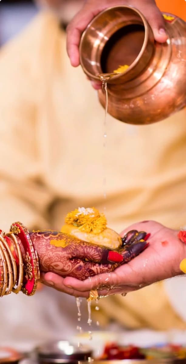Water poured from a copper vessel over cupped hands during a ritual