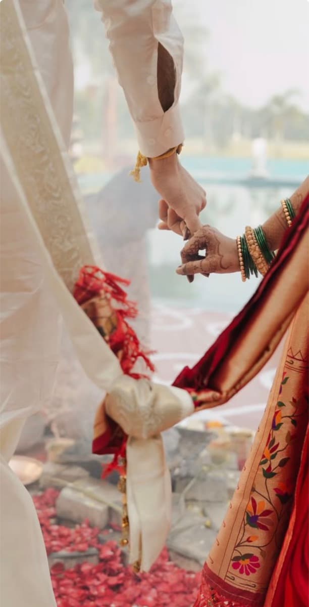 A couple walking hand in hand over rose petals in ceremonial dress